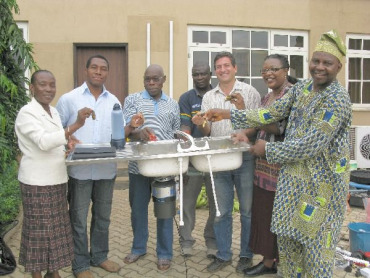 Former Nigerian President Oluwasegun Obasanjo demonstrates the Insinkerator Food Waste Grinder that Emerson Electronics gave him as a gift to use with his home biodigester.